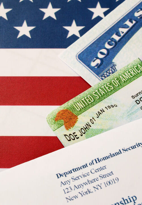 Cartões do Green Card e Social Security sobre uma bandeira dos Estados Unidos, ao lado de uma carta do Departamento de Segurança Interna.